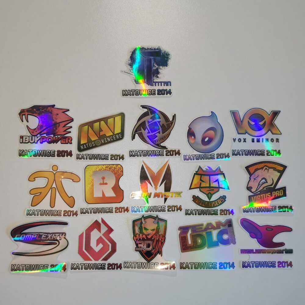 A physical spread of Katowice 2014 holo stickers — the digital versions now anchor six-figure inventories.